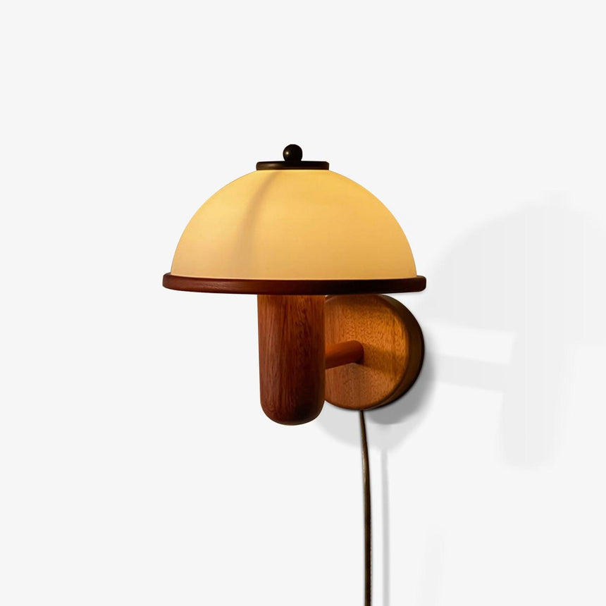 The dome shade lit warm, glowing amber above a dark oak arm