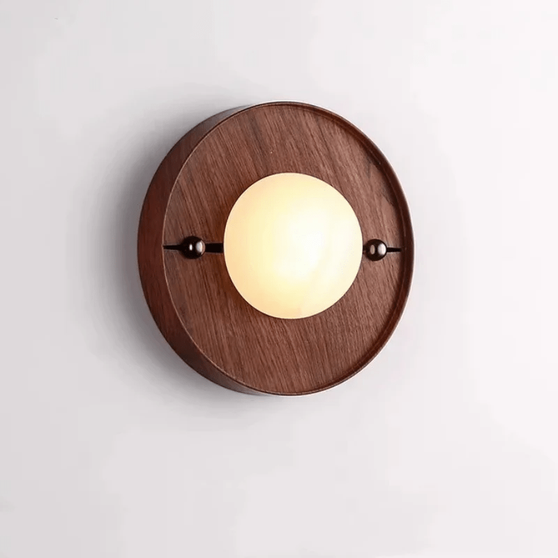 Alabaster orb lit warm on a round walnut plate seen straight on