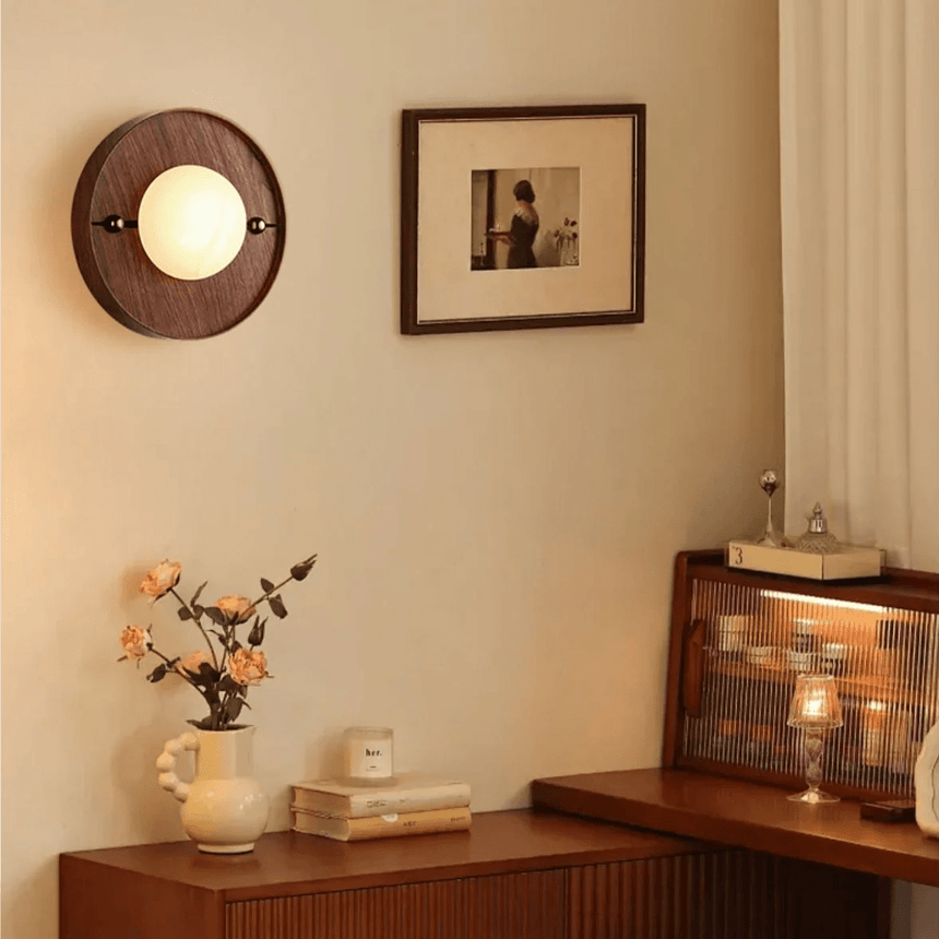 Alabaster orb on a round walnut plate on a wall beside a framed print