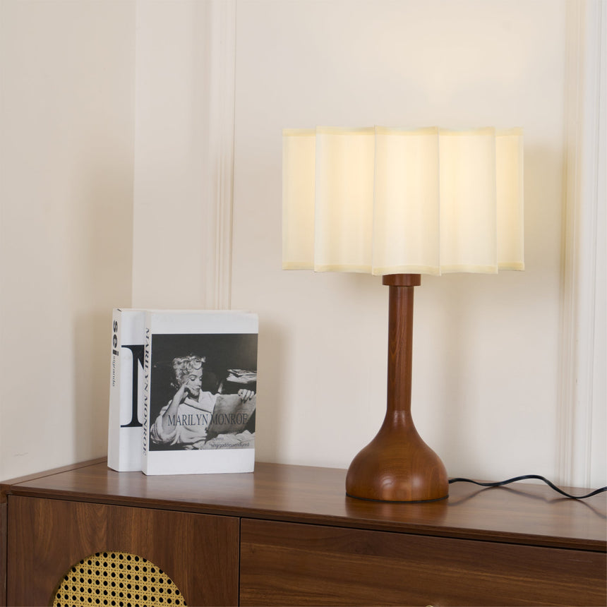 Beige table lamp lit on a sideboard beside a standing book