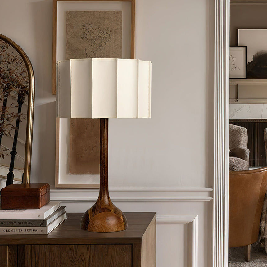 Beige table lamp lit on a console beside books and a box
