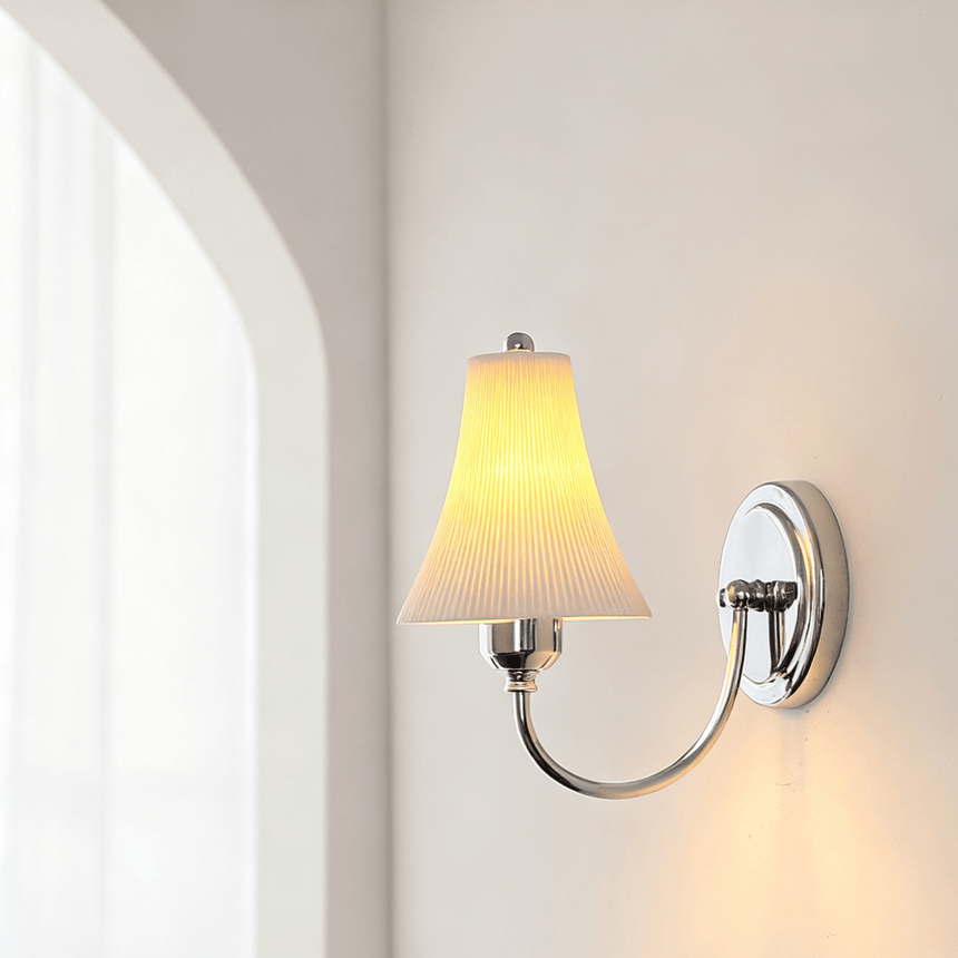 The sconce lit on a wall beside an arched doorway