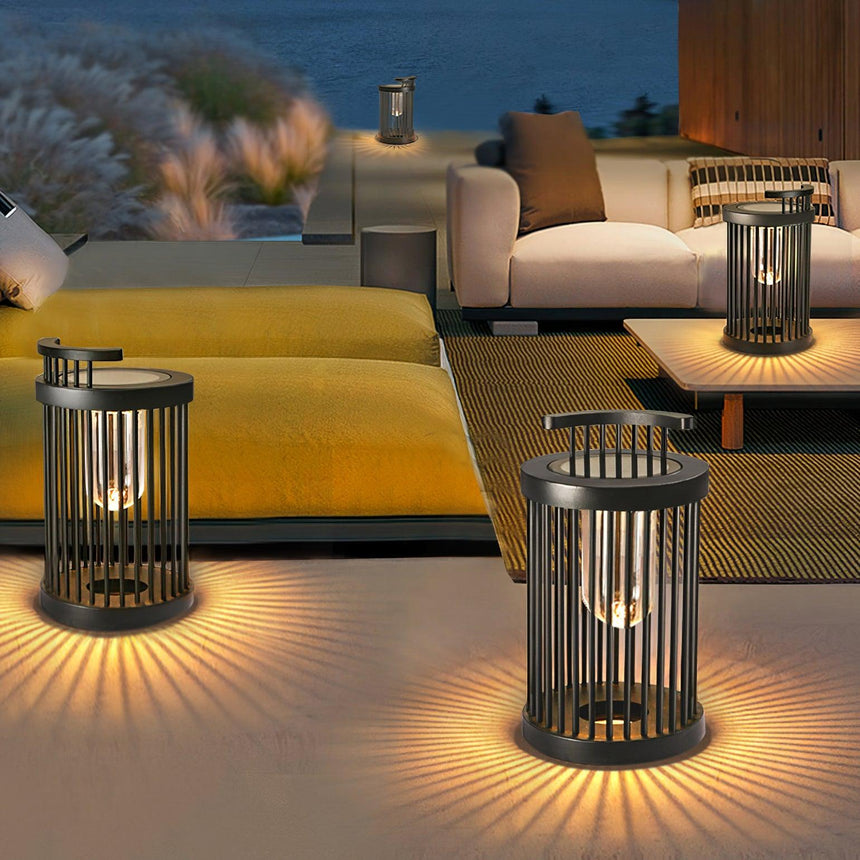 Three lanterns lit on a terrace beside a low sofa and a yellow daybed