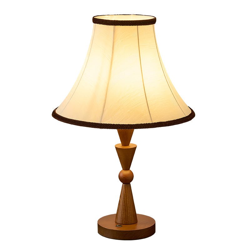 Cream empire shade lit from inside above the turned wood stem
