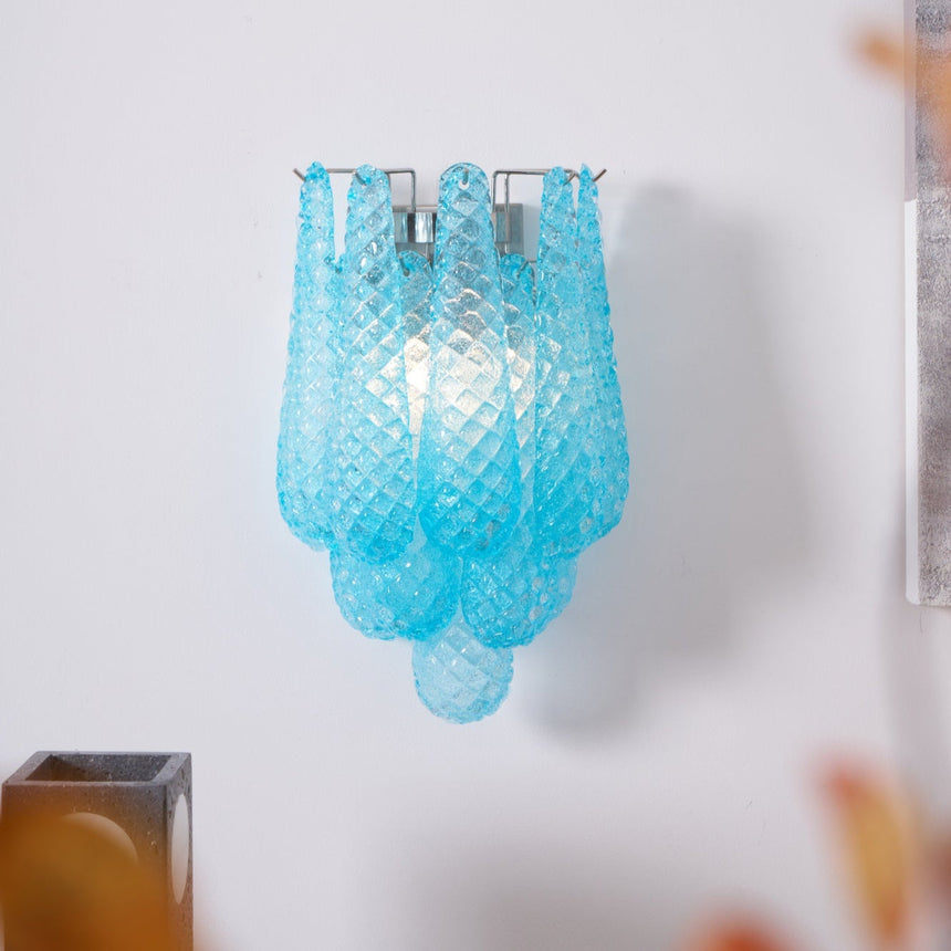 The blue sconce above a table with a patterned vase and candles