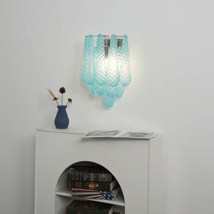 The blue sconce above a white cabinet with an arched niche and books