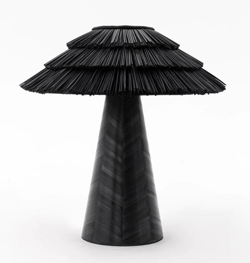 Black boho table lamp seen in full, straw tiers over a dark cone