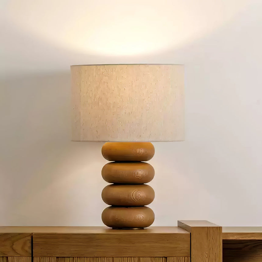 Stacked sphere table lamp unlit on a wood sideboard in a bright hallway