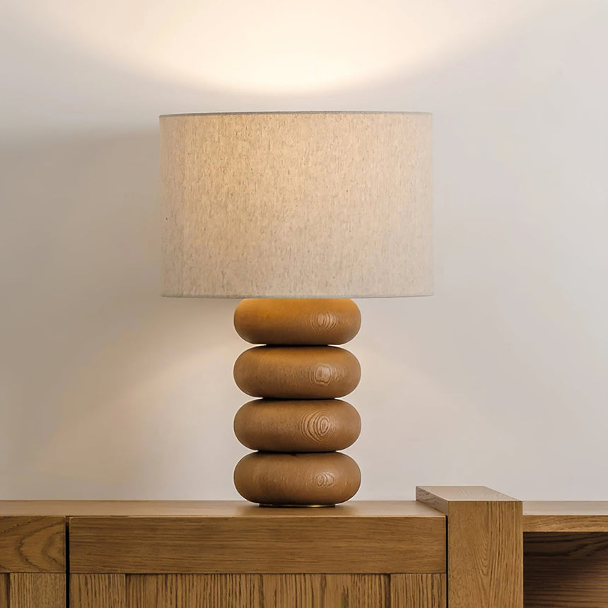 Stacked sphere table lamp lit on a wood sideboard against a pale wall