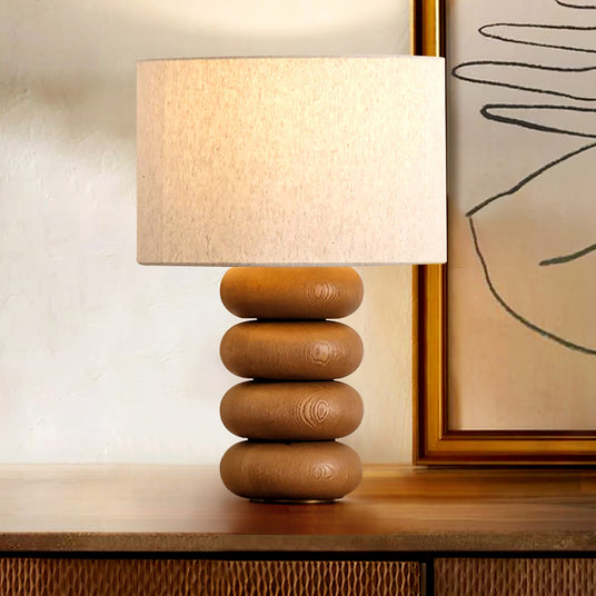 Stacked sphere table lamp lit on a sideboard beside a framed artwork