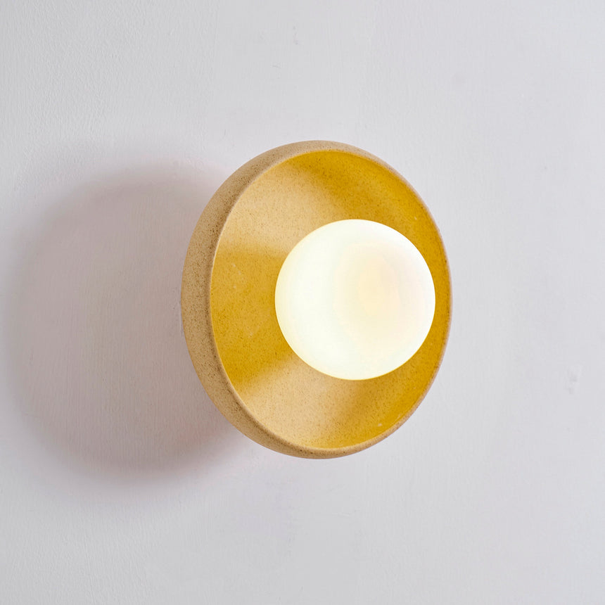 The bowl lit and seen from the side, light spreading across the wall