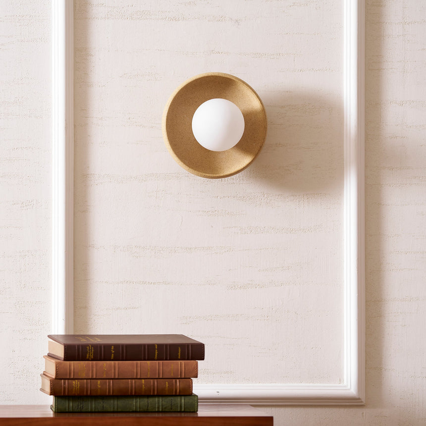 The sconce on a paneled wall above a stack of books on a wood chest