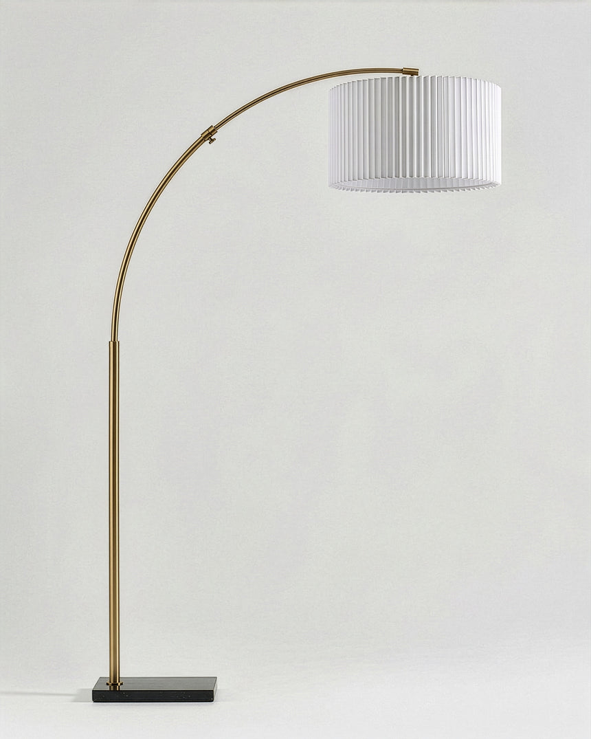 The same brass arc carrying a white pleated drum shade instead of plain linen