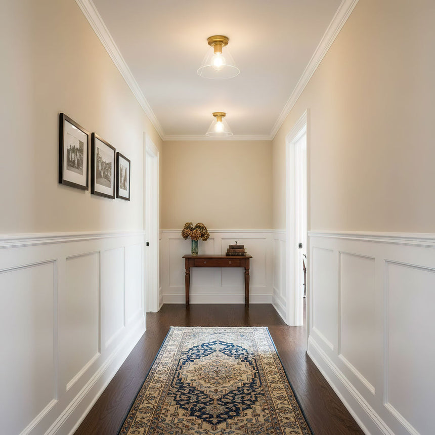 Brass ceiling light in a hallway with framed prints and a console table