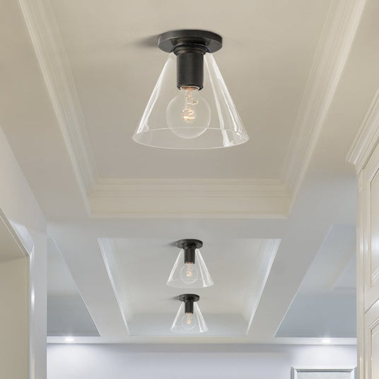 Black ceiling lights with cone shades in a white corridor with a stepped ceiling