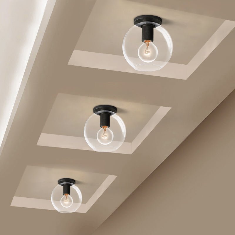 Three black ceiling lights with globe bulbs set in recessed ceiling panels