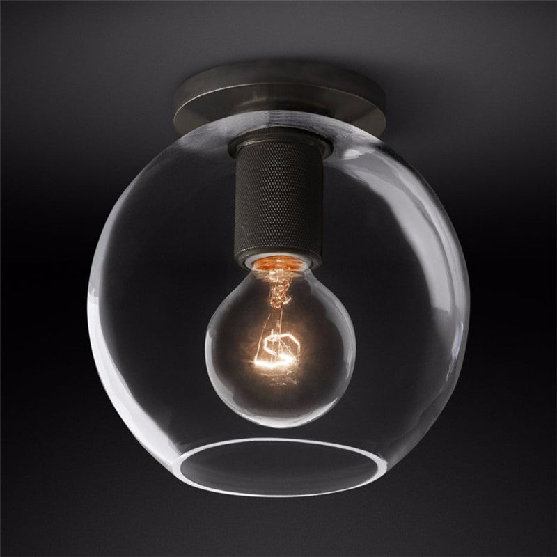 Black ceiling light with a clear globe shade against a dark backdrop