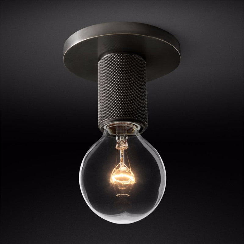 Black ceiling light with an exposed filament bulb against a dark backdrop