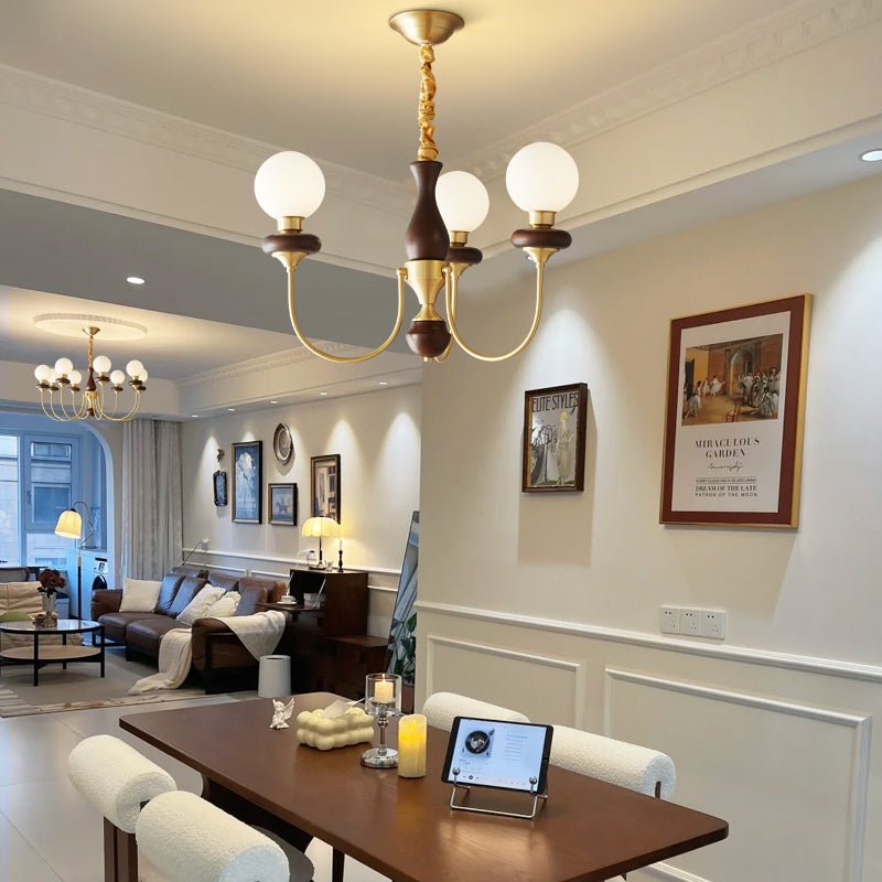 Chandelier lit in a dining room above a table with a mirror behind