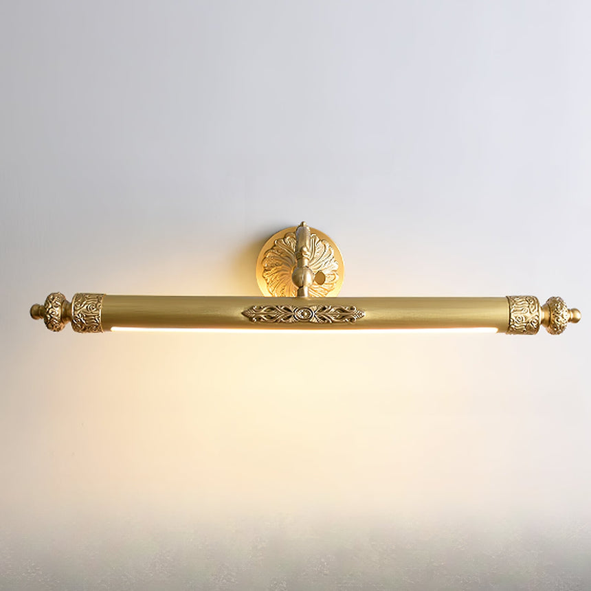 The brass bar lit on a pale wall, warm light spreading below the cast tube