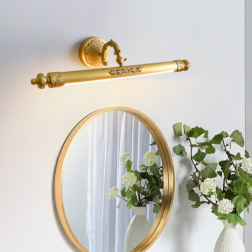 Brass bar lit above a round gold mirror beside a vase of white and blue flowers