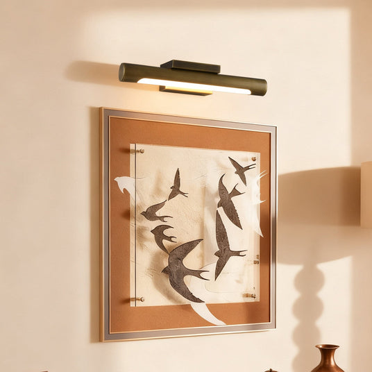 Bronze bar lit above a framed bird artwork on a warm plaster wall