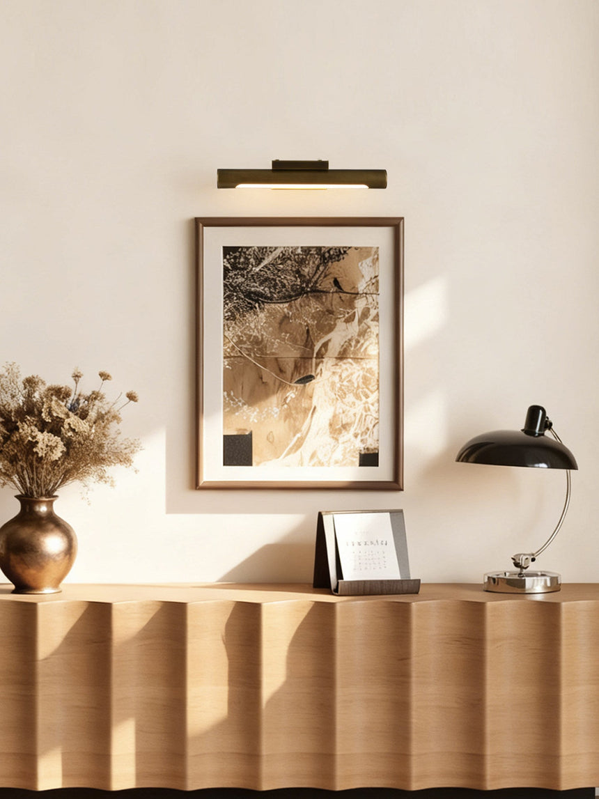 Bronze bar lit over a framed print above a fluted console with flowers