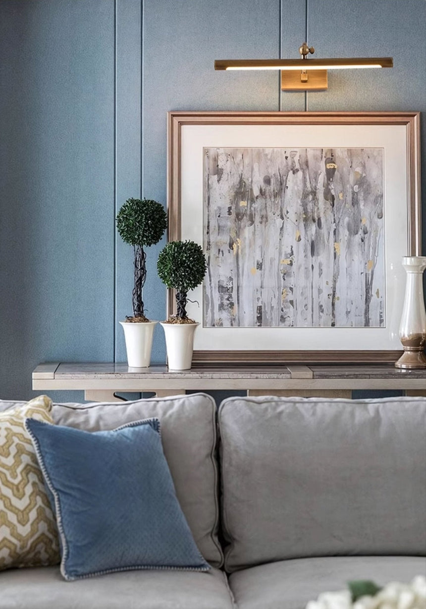 Bronze bar lit over a framed print above a sofa with blue and patterned cushions