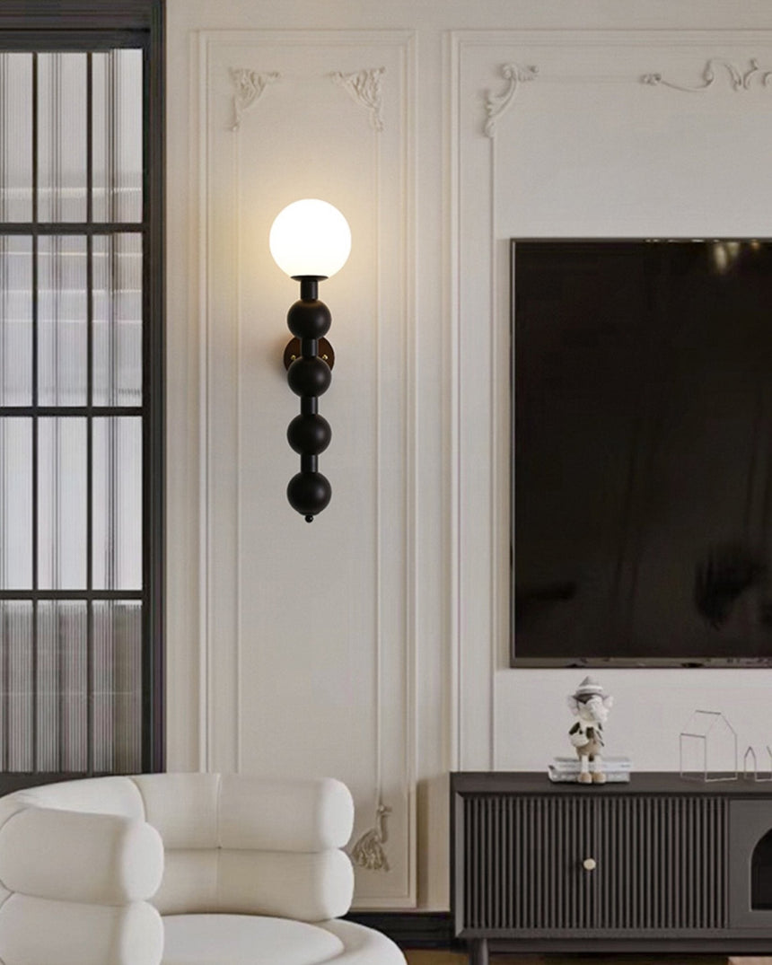 Sconce lit above a fluted console beside two pale armchairs