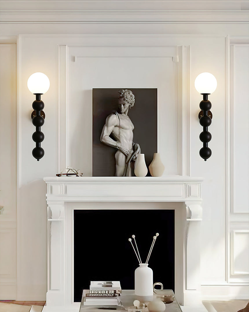 Two sconces lit either side of a white fireplace with a framed sculpture