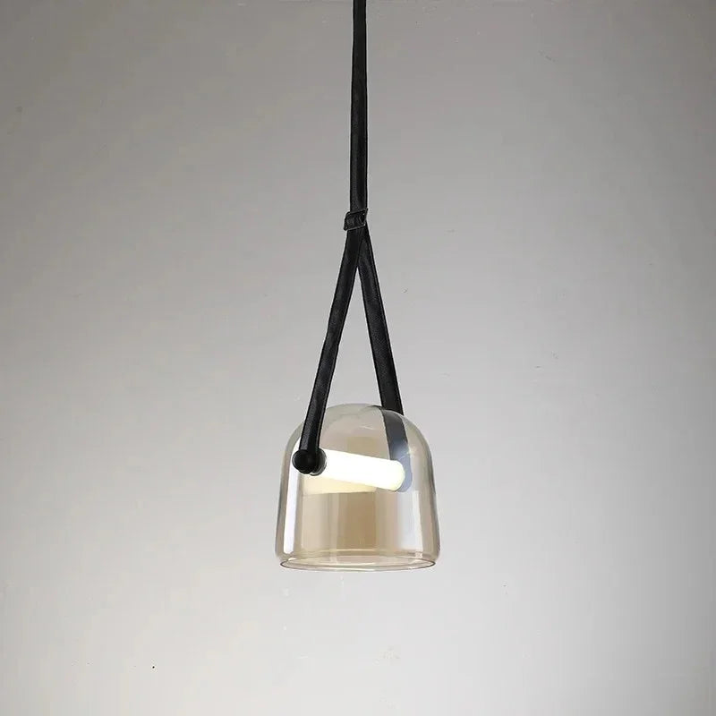 The amber plated glass shade on its leather strap on a plain background