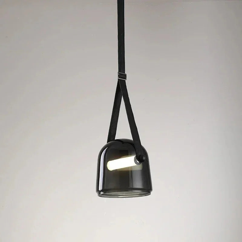 The black plated glass shade on its leather strap on a plain background
