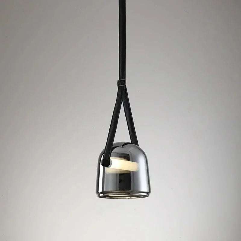 The gray plated glass shade on its leather strap on a plain backdrop