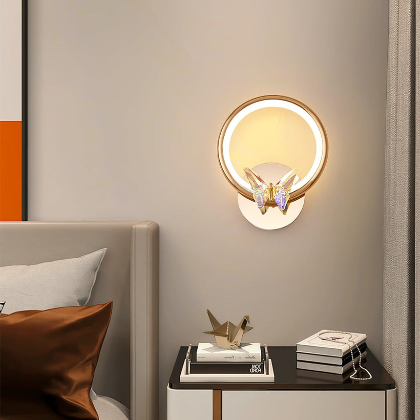 The butterfly ring lit above a black nightstand with books beside a bed