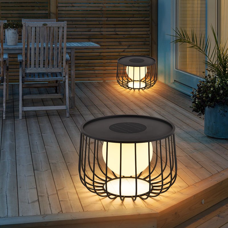 Two lanterns lit on a timber deck beside a chair and a planter at night