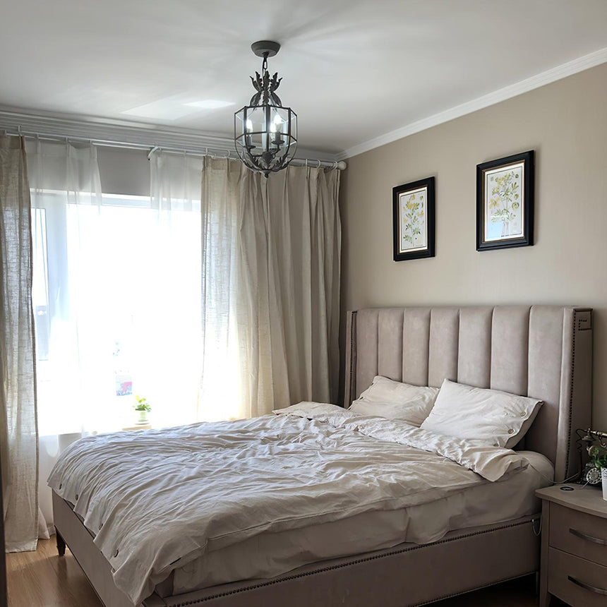 Hung in a bedroom above a made bed with long curtains and framed prints