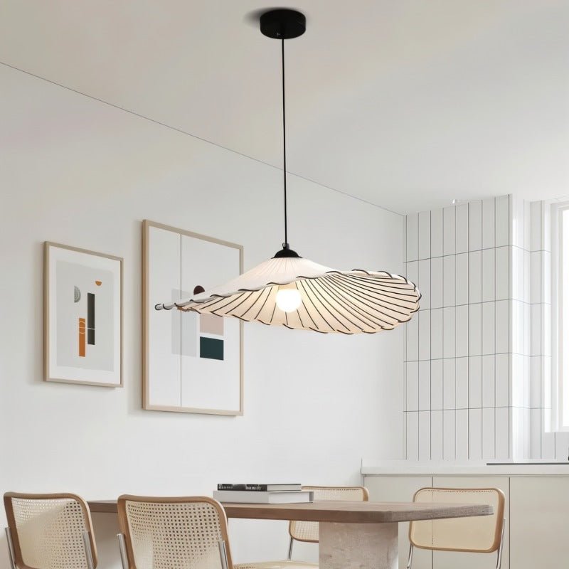 The flat shade over a kitchen counter with a vase of flowers and a hob behind
