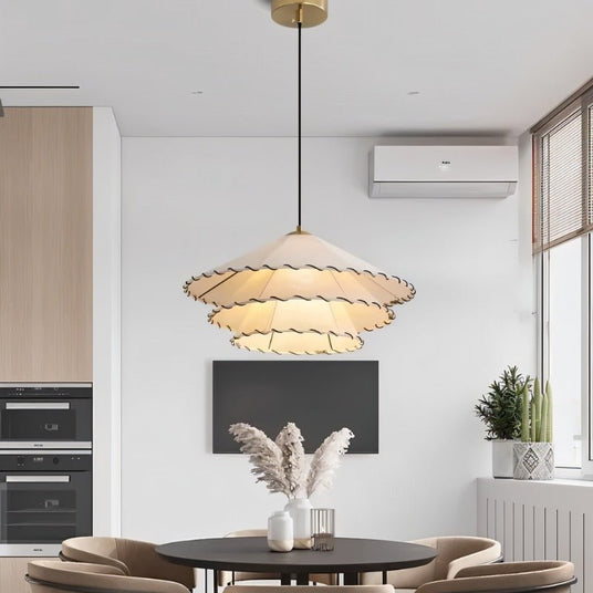 The flat shade lit over a kitchen table and chairs beside framed prints