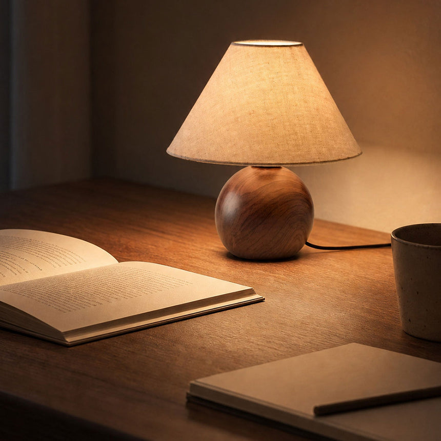 Ceramic bedside lamp lit on a desk beside an open book