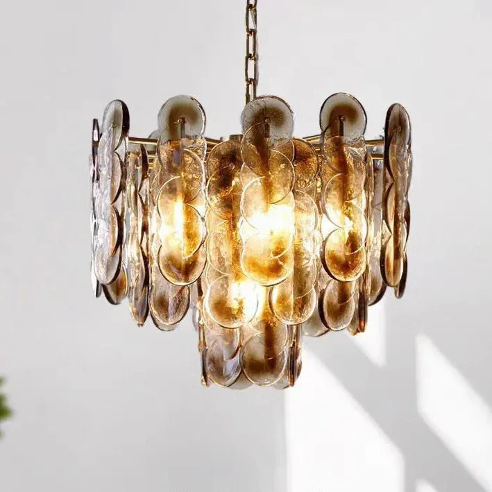 The amber glass petal chandelier lit against a pale wall