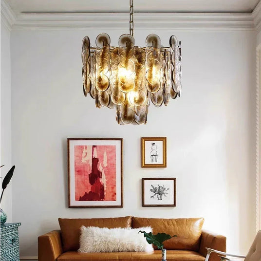 The amber petal chandelier lit above a sofa with framed pictures behind