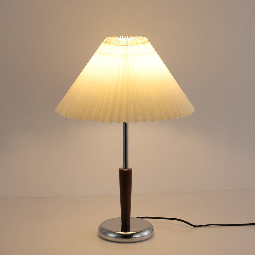 Chrome table lamp lit, the cord running away across the surface