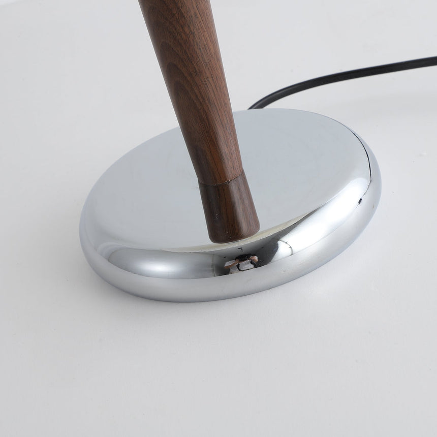 Close view of the low oval chrome foot with the walnut stem rising from it