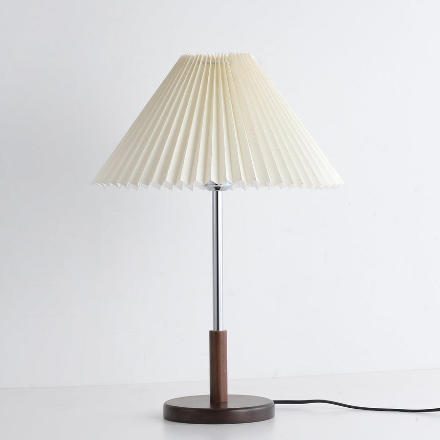 Chrome stem table lamp unlit against a pale ground, pleats clearly visible