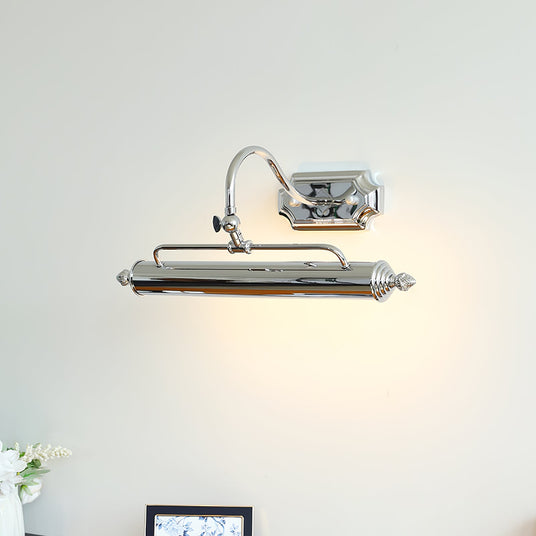 Chrome bar lit above a small framed print standing on a wood desk with flowers