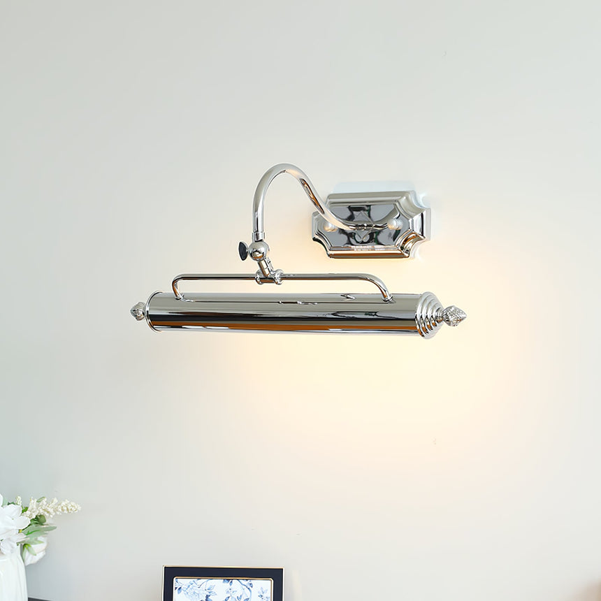 Chrome bar lit above a small framed print standing on a wood desk with flowers