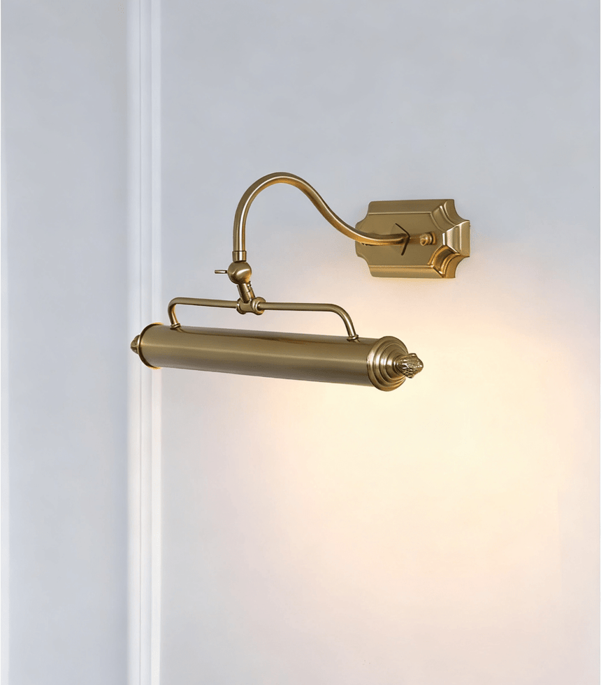 The gold version lit on a pale wall, the arched arm rising to the turned bar