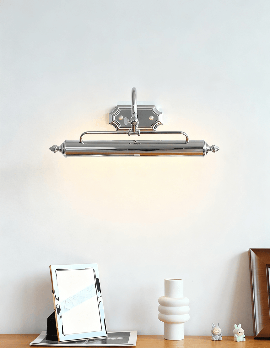Chrome bar lit above a folding mirror and pale vases on a wood desk