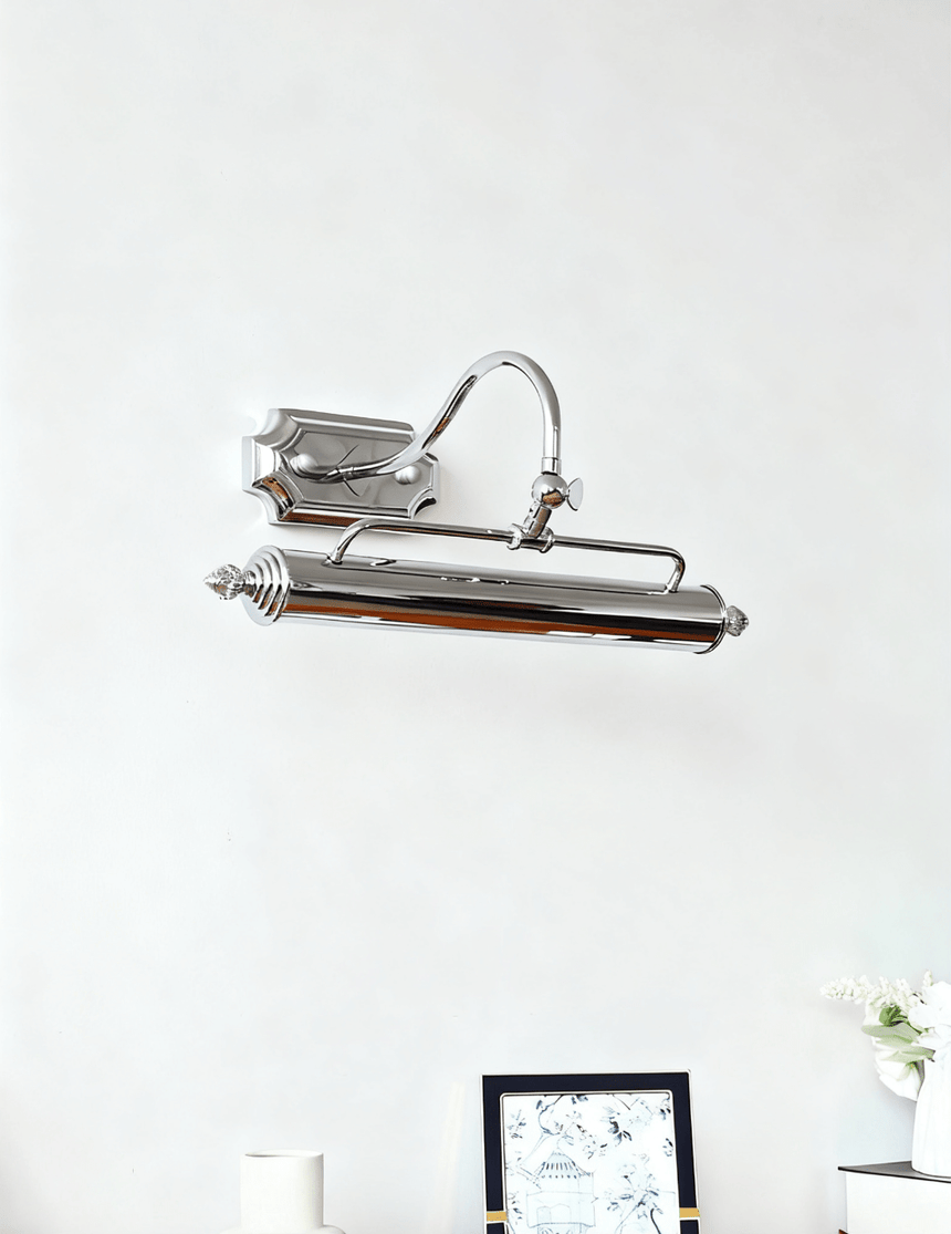 The chrome bar unlit on a pale wall above a small dark framed picture