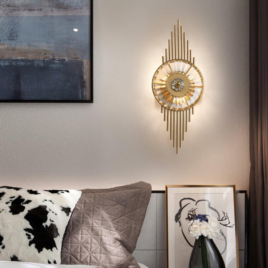 The sconce lit above a bed with patterned pillows beside a framed painting